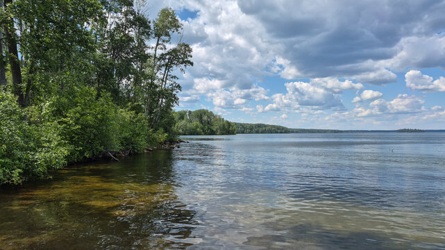 Tranquil Canadian Freshwater Lake Surrounded by Forest and Towering Cumulus Clouds