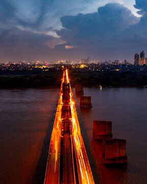 Aerial view of the historic Long Bien Bridge illuminated at night with light trails from traffic crossing over the Red River in Hanoi, Hanoi, Vietnam.