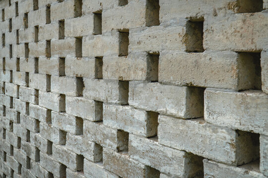 Concrete ventilation block wall with geometric openings, creating a modern architectural texture and repeating abstract pattern.