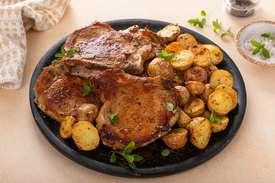Pork chops on a bone grilled or sauteed served with roasted potatoes on a plate
