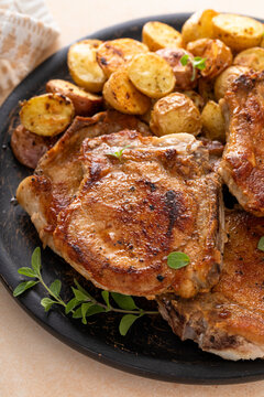 Pork chops on a bone grilled or sauteed served with roasted potatoes on a plate