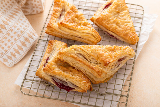 Puff pastries turnovers with cherry or berry jam on a baking sheet freshly baked and ready to eat