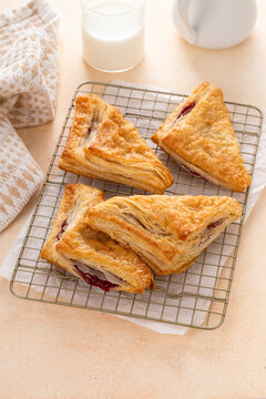 Puff pastries turnovers with cherry or berry jam on a baking sheet freshly baked and ready to eat