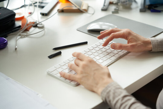 Typing on a keyboard at a workspace during the day