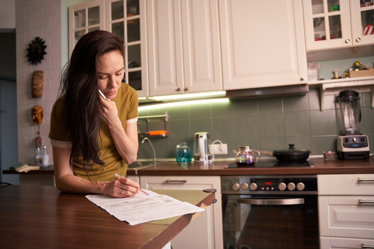 Woman reviewing utility bills in a modern kitchen