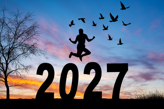 Happy group of people celebrate jump for new year 2027. concept for win victory. silhouette of friends jumps at sunset time on mountains.