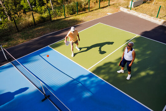 Elder couple enjoying active game on pickleball court