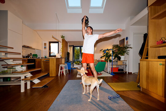 Man exercises in the living room with his dog  nearby