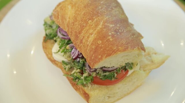 Mediterranean ciabatta sandwich served on a white plate in a kitchen