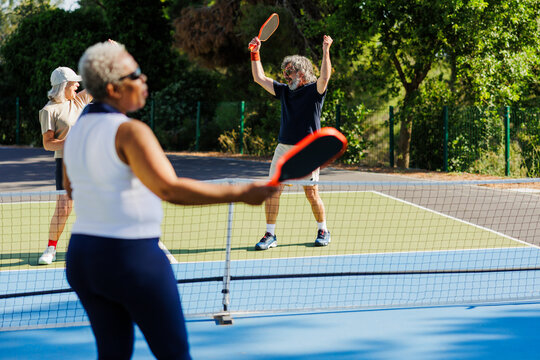 Active friends playing pickleball on outdoor court