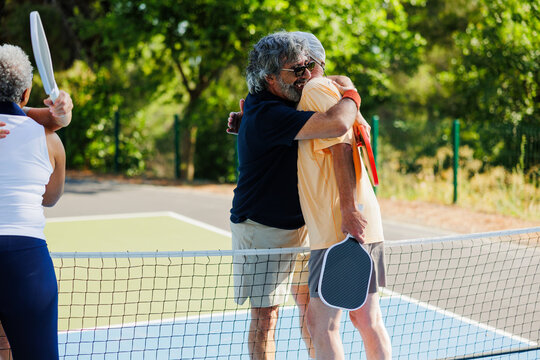 Hugging pickleball players celebrating game victory on court