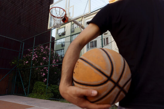 A young man is holding a basketball in his hand.
