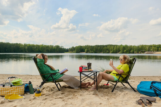 Women Relaxing with Books at a Lakeside Campsite