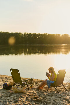 Woman Relaxing with Coffee at Sunset by the Lake
