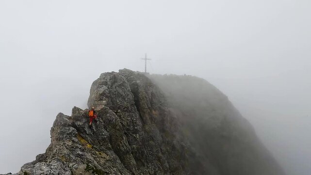 A hiker walking to the summit cross of Ehrwalder Sonnenspitze in the Austrian Alps of Tyrol, Austria