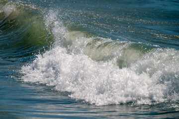 Naklejka premium A refreshing, vibrant ocean wave curls and crashes into a dynamic burst of white sea foam under bright sunlight