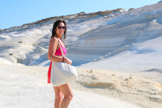 Beautiful woman exploring Sarakiniko in Milos, Greece, enjoys travel and adventure among white rock formations and scenic coastal landscape, capturing a summer vacation in the Mediterranean.