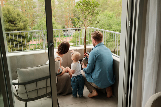 Anonymous parents watering the tree at the patio with their child 