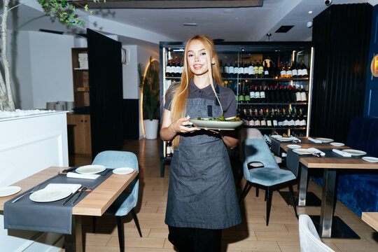 Waitress serving meal in modern restaurant interior