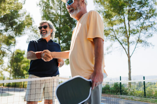 Seniors shaking hands on pickleball court after game