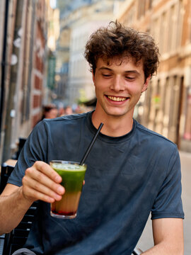 Young Man Enjoys Drink in City Street During Warm Afternoon