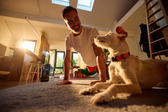 Active man exercises at home in the presence of his dog