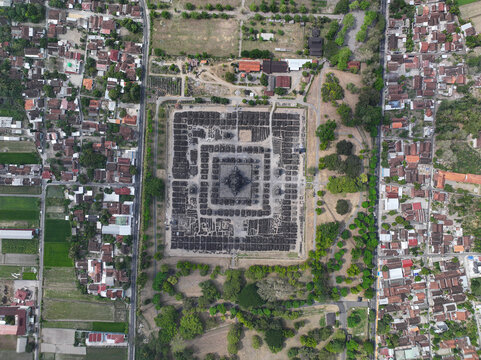 Aerial view of the ancient Sewu Temple complex with its symmetrical layout surrounded by lush trees, rural houses, and fields in Kecamatan Prambanan, Daerah Istimewa Yogya, Indonesia.