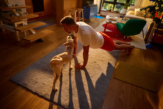An energetic man performing push-ups alongside a dog.
