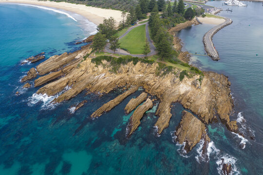 Coastal parkland above a rocky headland jutting out into a blue ocean
