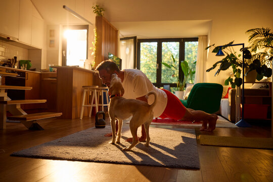 An active man works out at home with his dog by his side.