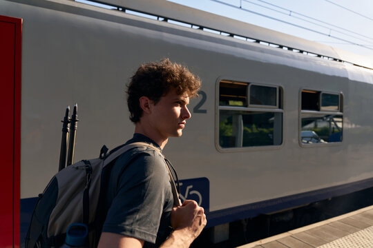 Young Man Waits at Train Station for Arrival of Train