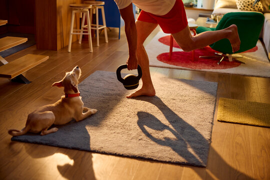Man workouts in the living room with his dog lying nearby