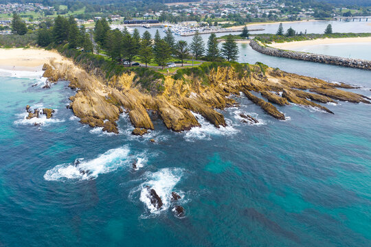 Coastal parkland above a rocky headland jutting out into a blue ocean