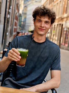 Young Man Enjoys Drink in City Street During Warm Afternoon