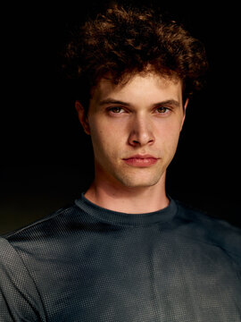Young Man Poses for a Close-Up Shot Indoors in a Dark Setting