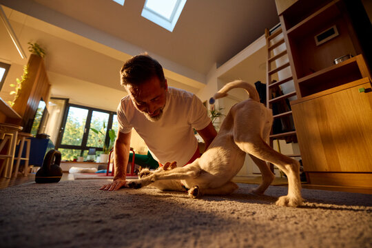 Happy man exercising in the apartment with his dog