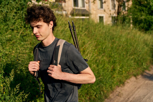 Young Man Walks on a Path With a Backpack and Walking Sticks