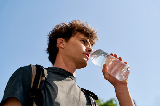 Young Person Drinks Water During Outdoor Activity on a Sunny Day
