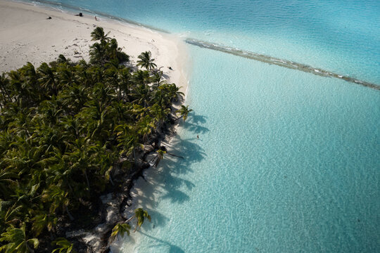 Aerial view of Honeymoon Island - Maina Iti with a pristine white sand beach, lush palm trees, and clear turquoise waters in the Cook Islands.