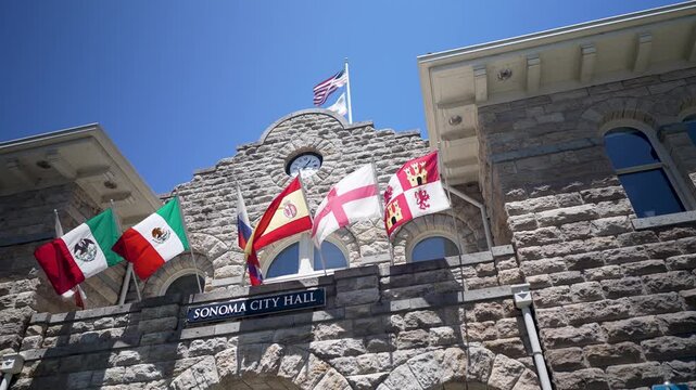 Flags from different regions fly at Sonoma City Hall in downtown Sonoma California under a clear blue sky on a sunny day