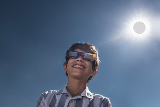 Smiling Boy Wearing Solar Eclipse Glasses Under the Sun