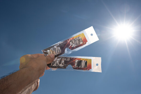 Hand Holding Solar Eclipse Glasses Against the Sun
