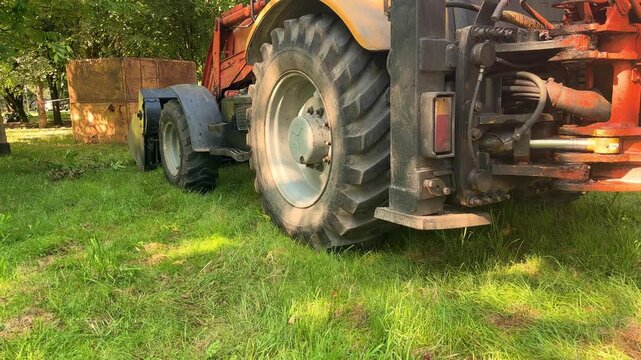 Backhoe loader parked on grass in summer, heavy construction machinery, earthmoving equipment, industrial work vehicle.