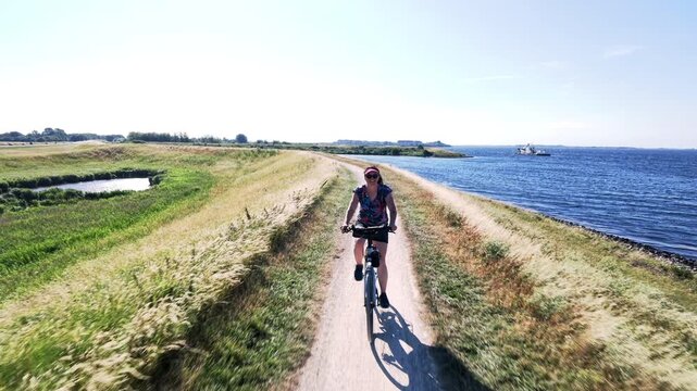 Woman cycling along a seaside dike in the Netherlands
