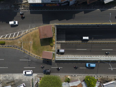Aerial view of Perempatan Kentungan intersection with vehicles moving through the underpass and surrounding roads in Kecamatan Mlati, Daerah Istimewa Yogya, Indonesia.