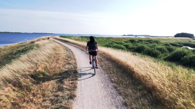 Woman cycling along a seaside dike in the Netherlands
