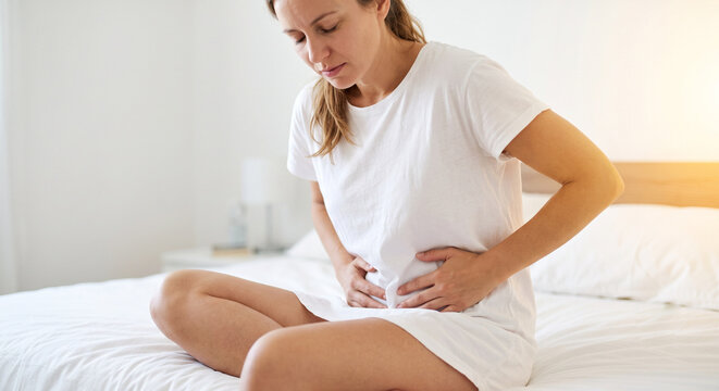 Young woman holding her lower abdomen in pain, suffering from chlamydia infection or pelvic inflammatory disease.