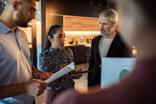 Diverse coworkers discussing reports in a modern office kitchen
