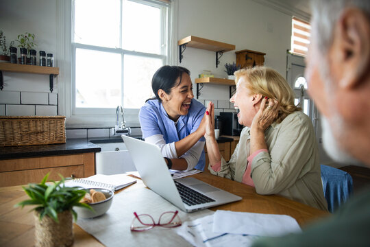 Home healthcare nurse and senior high five in kitchen