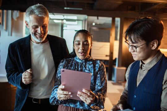 Coworkers collaborating with tablet in modern office